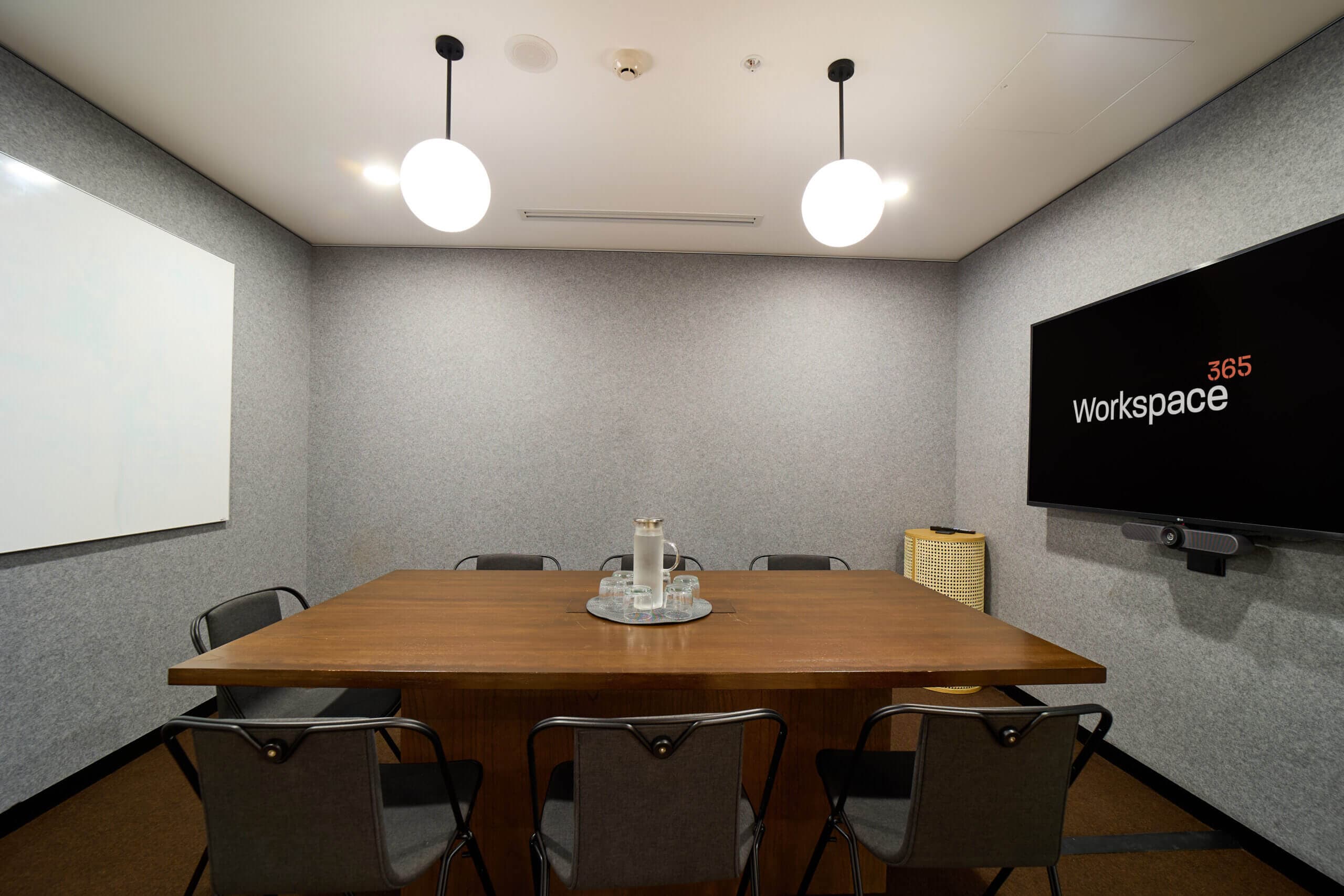 Small meeting room with conference table, chairs, whiteboard, and a large screen.