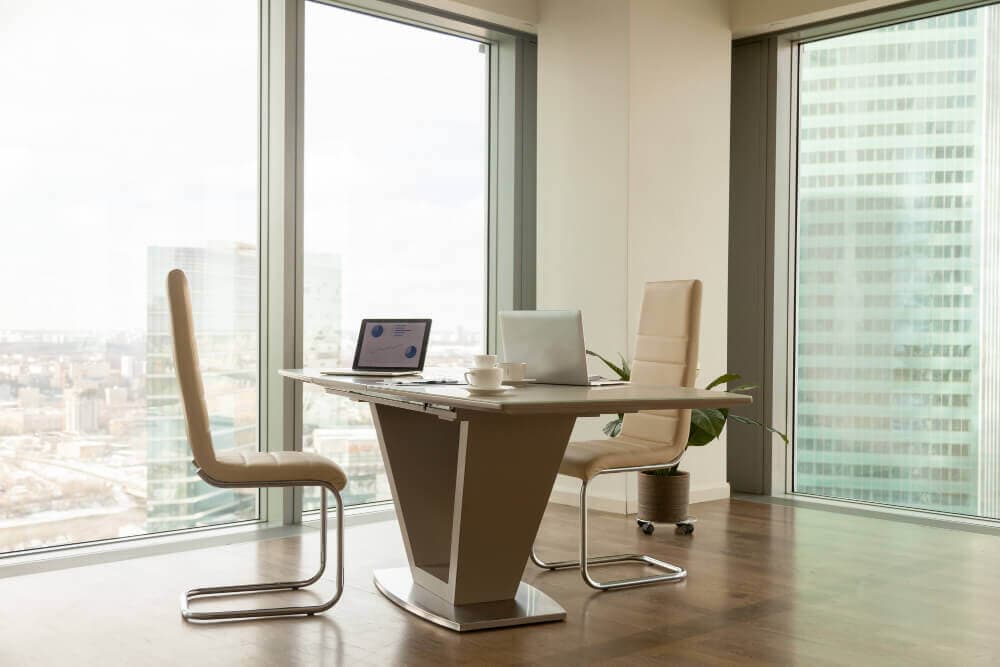 Modern private office with a sleek desk, two chairs, and large windows overlooking the city